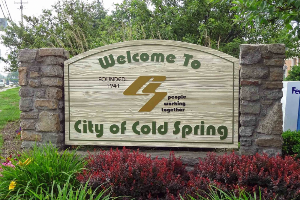 Cold Spring Kentucky | Davis Landscape Design & Installation Wooden welcome sign for the City of Cold Spring between stone pillars, with greenery and a flower bed in front.