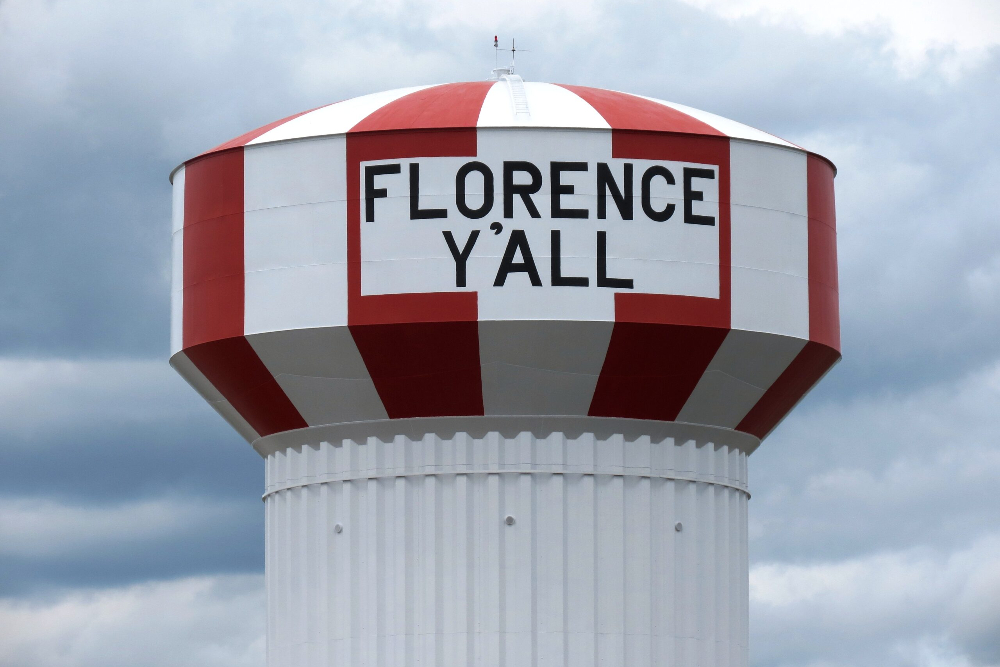 Florence-Kentucky | Davis Landscape Design & Installation Water tower with red and white stripes and the sign 'FLORENCE Y'ALL' against a cloudy sky.