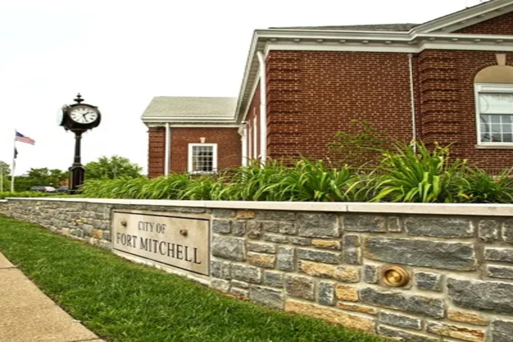 fort-mitchell-city-building | Davis Landscape Design & Installation Sign reading 'City of Fort Mitchell' on a stone wall in front of a red brick municipal building, with a decorative clock post and greenery nearby