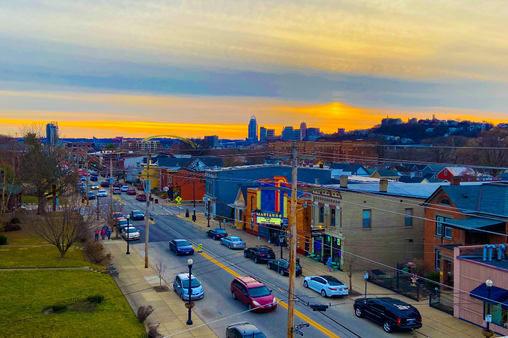 Bellevue KY | Davis Landscape Design & Installation City street scene at sunset with a downtown skyline on the horizon and cars driving along a busy road.
